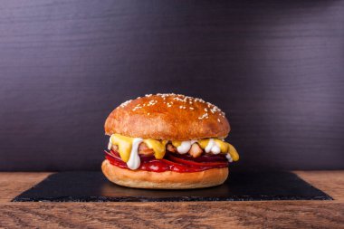 Salamura edilmiş soslu tavuk, domates, soğan ve soslu ahşap zemin. Tavuk göğsü ve patates dilimli hamburger.