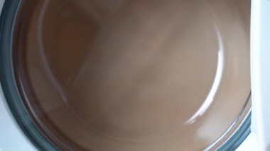 Kurutma aşaması çamaşır makinesinin hızını kademeli olarak artırıyor. Cam kapı görünüyor, giysiler çok hızlı dönüyor. Ön yükleme makinesinin kurutma aşaması. Çamaşır Makinesi.