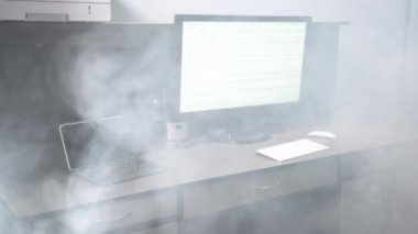 Masaüstü bilgisayarı duman içinde. Aşırı ısınmış elektronik aletler donanım arızası yaratıyor. Duman masanın altından geliyor.