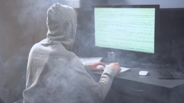 Bilgisayarda çalışan ve arka planda sigara içen genç bir programcı. Operatör bilgisayarda daktilo ediyor. Odada sigara iç.
