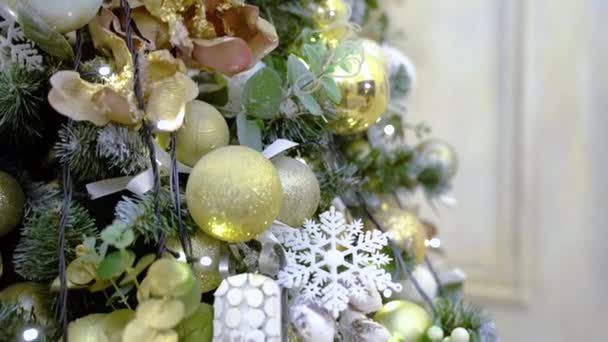 Boże Narodzenie dekorowane drzewo zbliżenie. Noworoczne bombki. Nagranie panoramiczne złotych kulek, bombki i girlandy zdobiące choinkę w domu — Wideo stockowe