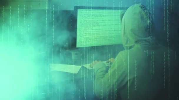 Atak hakerów. Haker Wejdź do zielonej matrycy. Haker w kapturze spogląda na monitor z wyświetlanymi numerami kodu i znakami. Dym na tle — Wideo stockowe