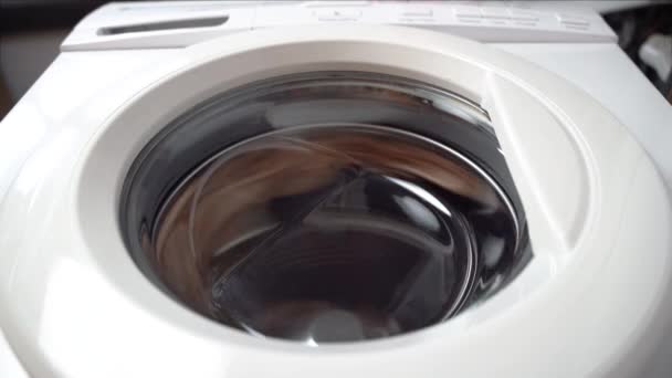 Washing machine finishes spinning and things fall on the glass door. Front view from bottom, an unusual perspective — Stock Video