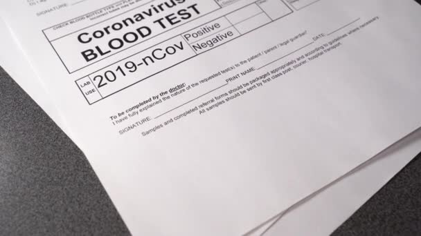 Koronavirus Pozitivní test. Ruka zdravotnického pracovníka s modrými chirurgickými rukavicemi označujícími výsledky krevních testů jako pozitivní na COVID-19 na bílé testovací stránce. Infekce virem pandemie korony — Stock video