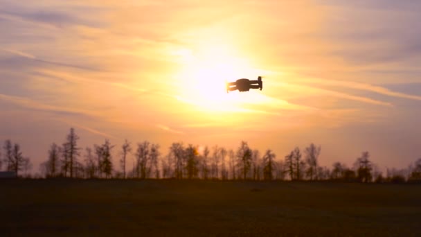 Quadcopter Volando en el fondo de la hermosa puesta del sol y el bosque. Quadcopter se cierne en el aire — Vídeos de Stock