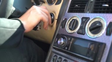Adam anahtarlarını sokete takıp motoru çalıştırıyor. Araba anahtarlı bir adam. Yanan araba. Sürücü bir arabanın vitesini hareket ettirir