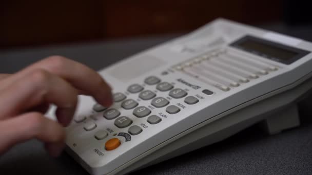 Männer wählen auf den Nummerntasten des kabelgebundenen Telefons. Niedrige Nahaufnahme der männlichen Hand, die Hörer aufnimmt und die Telefonnummer auf der weißen Festnetztastatur wählt. — Stockvideo