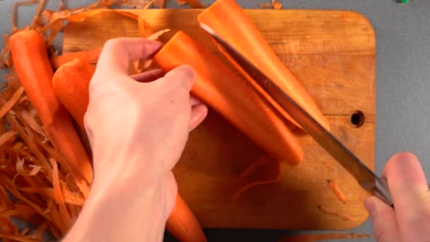 Hombre cortando una zanahoria a mano en una mesa de cortar. Top View Cuchillo Chef Masculino Cortado Verduras — Vídeos de Stock