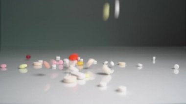 Tabletler ve haplar ağır çekimde masaya düşüyor. Uyuşturucuyu bırak. Zorunlu aşılar, koronavirüse karşı ilaçlar