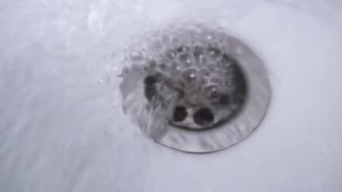 Beyaz bir mutfak lavabosunun deliğini yakınlaştır. Su musluktan deliğe akar.