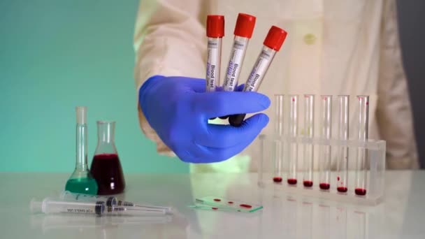 Main dans les gants tenant des éprouvettes avec échantillon d'essai en laboratoire. Test du coronavirus sanguin en laboratoire — Video