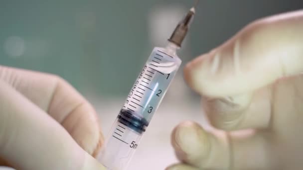 Medische hulpverlener tikt op een spuit. Vóór injectie lucht uit een spuit verwijderen — Stockvideo