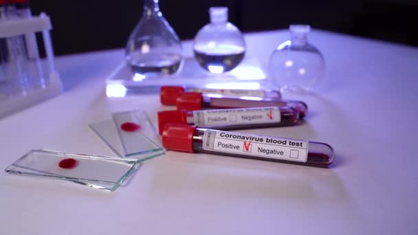 Tubo di prova e vetro di prova con campione di sangue infetto per COVID-19 sul tavolo di laboratorio medico. Ricerca sui vaccini per il virus SARS nCoV — Video Stock