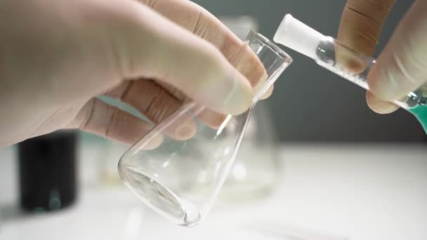 Gli scienziati versano sostanze chimiche da una bottiglia di vetro. Scienziato che versa Chimica in un Flask. Ricerca di un vaccino contro il coronovirus — Video Stock