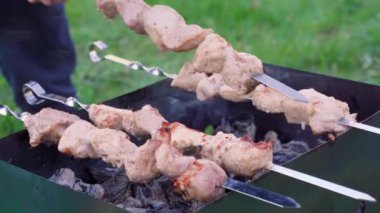 Adam kebapları bıçakla kontrol ediyor. Açık hava barbeküsü. Kızarmış çiğ et.