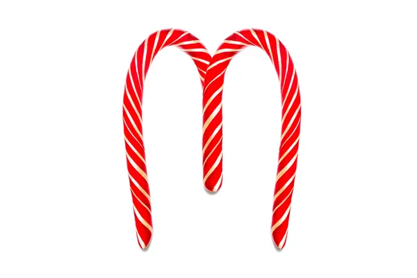 Symbol M vytvořený ze slavnostních ozdobných červených bonbónů. M Prázdninový text z červené cukrové třtiny. — Stock fotografie