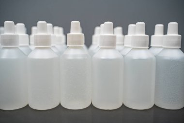 Gri arka planda bir sürü dezenfektan şişesi var.