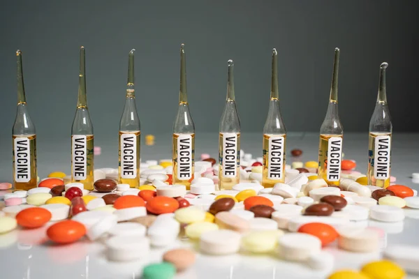 Muchas tabletas y píldoras delante de frascos de vidrio vacuna. Vacunaciones obligatorias, vacuna del coronavirus — Foto de Stock