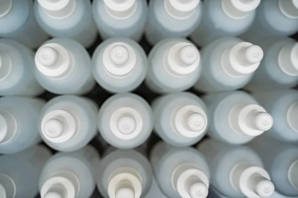 Många vita flaskor fyllda med vätska. Tillverkning av antiseptika Royaltyfria Stockbilder