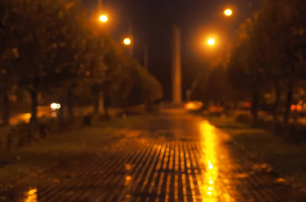 Fondo borroso de la ciudad lluviosa nocturna. Luz de neón — Foto de Stock
