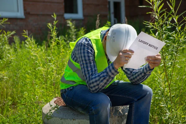 Worker reads the layoff notice outdoor. Unemployment concept. Coronavirus aftermath.