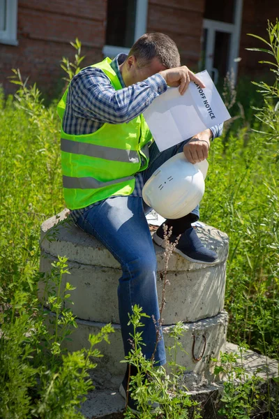 Worker reads the layoff notice outdoor. Unemployment concept. Coronavirus aftermath.