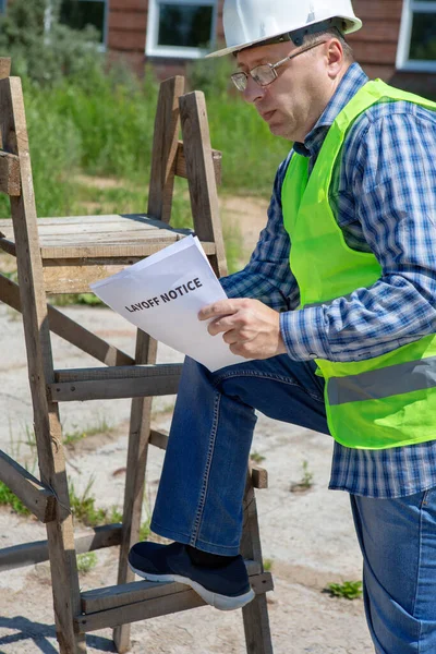 Worker reads the layoff notice outdoor. Unemployment concept. Coronavirus aftermath.