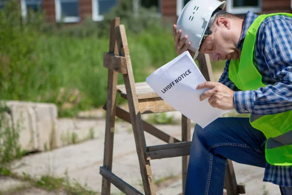 Worker reads the layoff notice outdoor. Unemployment concept. Coronavirus aftermath.