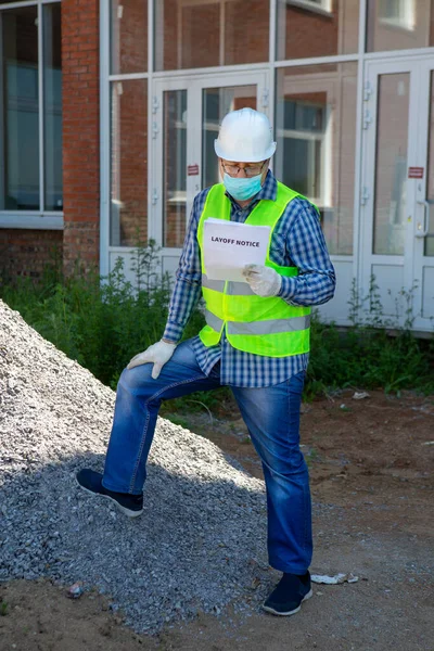 Worker reads the layoff notice outdoor. Unemployment concept. Coronavirus aftermath.