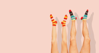 Komik çizgili çoraplar. Evli bir çiftin bacakları. Mercan Pembesi 'nde izole edilmiş.