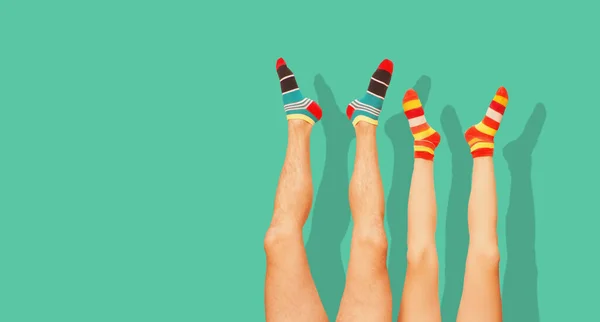 Funny striped socks. Legs of a married couple. Isolated on the green.