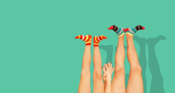 Funny striped socks. Legs of a married couple. Isolated on the green.
