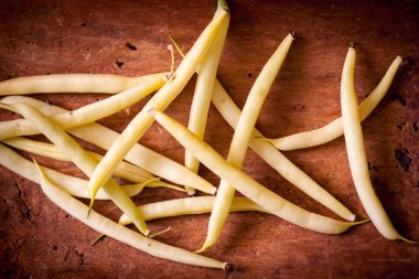 bir eski püskü ahşap yüzeyde birkaç sarı-yeşil ham fasulye bakla