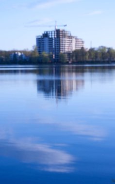 beautiful view of the unfinished house on the opposite side of the urban lake against the blue sky