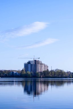 beautiful view of the unfinished house on the opposite side of the urban lake against the blue sky