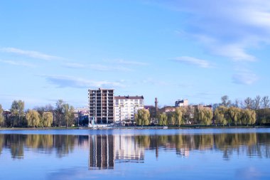 beautiful view of the unfinished house on the opposite side of the urban lake against the blue sky