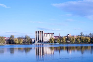 beautiful view of the unfinished house on the opposite side of the urban lake against the blue sky