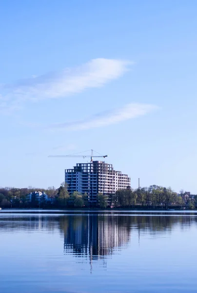 beautiful view of the unfinished house on the opposite side of the urban lake against the blue sky