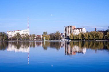 beautiful view of the unfinished house on the opposite side of the urban lake against the blue sky