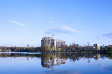 beautiful view of the unfinished house on the opposite side of the urban lake against the blue sky