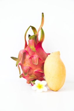 Beyaz arka planda beyaz bir plumeria çiçeğiyle birlikte egzotik Tayland meyveleri. Mango ve ejderha meyvesi.