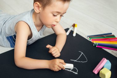 Anaokulu çocuğu mektup yazıyor. Çocuğun elindeki tebeşirle yakın çekim. Çocuk mektup yazmayı öğreniyor.