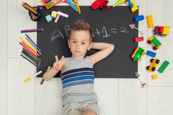 Vrolijk lachend jongetje ligt op zijn tekening — Stockfoto