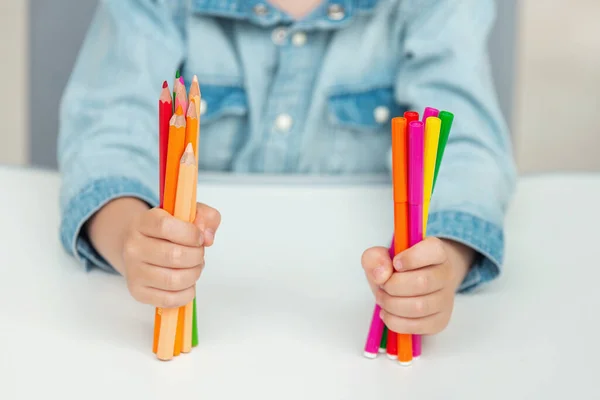Un niño sostiene bolígrafos y lápices de fieltro. Concepto escolar — Foto de Stock