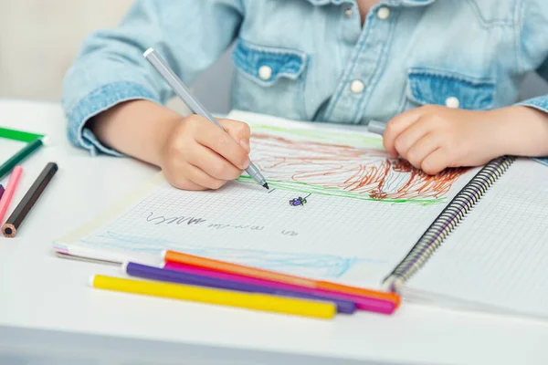 Preescolar dibuja en su cuaderno marcadores de colores y lápices — Foto de Stock