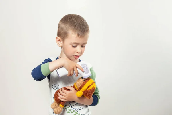 Маленький ребенок измеряет температуру для игрушечного медведя — стоковое фото