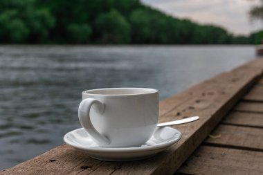 Bulanık nehir manzaralı arka planda beyaz bir bardak içki.