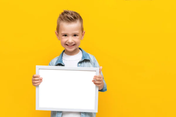 Joyeux enfant souriant tenant cadre blanc avec espace de copie pour certificat de texte ou diplôme — Photo