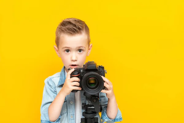 Adorable chico tomando una foto usando una cámara digital en un trípode —  Fotos de Stock