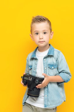 Elinde fotoğraf makinesi olan küçük bir çocuğun portresi.